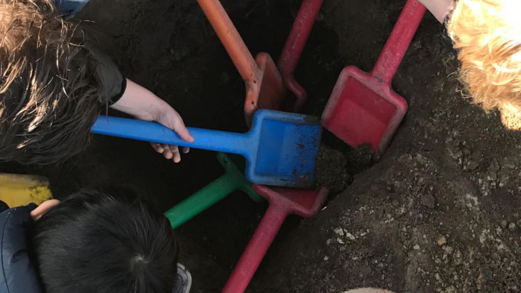 Kinderen met schepjes in zandbak