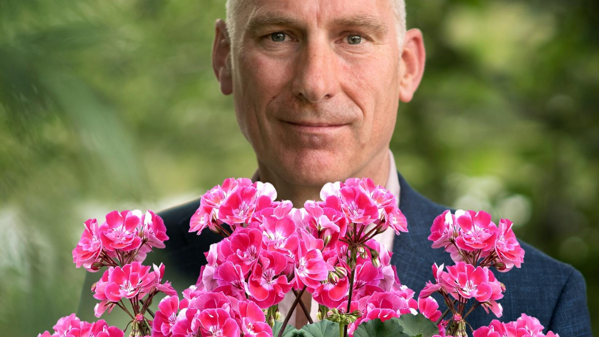 een foto van Peter Bakker, fractievoorzitter GroenLinks Breda, met op de voorgrond geraniums
